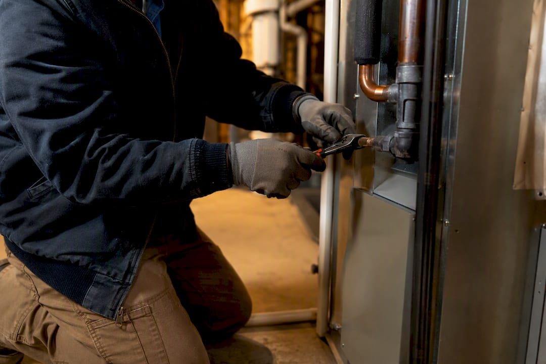 Technician tightening HVAC unit screw during repair